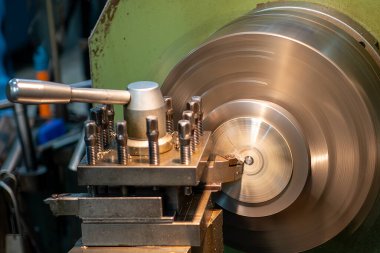 Kapanış sahnesinde torna makinası, açık mavi sahnedeki metal parçaları kesmiş. Makineyi döndürerek metal işleme süreci.