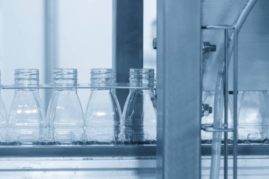 Taşıyıcı banttaki boş içme suyu şişeleri doldurmak için. İçme suyu üretim sürecinin yüksek teknolojisi. 