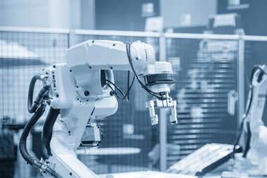 Açık mavi sahnede robotik sistem tarafından yapılan yüksek teknoloji madde işleme süreci. Akü üretim hattında robotik kol ile materyal işleme süreci. 