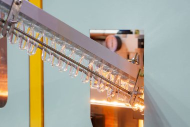 Taşıyıcı bant, önceden şekillendirilmiş şekli üfleme makinesine teslim eder. Plastik şişe üfleme makinesi operasyonu..