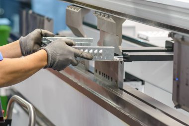 Bükme makinesi operatörünü kapatın ve metal parçaları koruyucu eldivenle tutun. Yetenek operatörünün kullandığı levha metal çalışması.