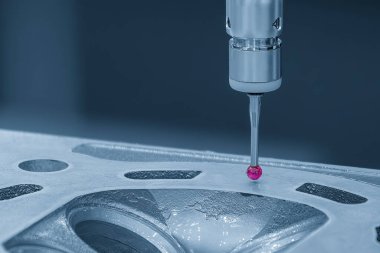 Açık mavi sahnede alüminyum silindir kafa parçalarını ölçen CMM makinesi. Çoklu eksen CMM makinesi ile otomotiv parçalarının kalite kontrolü