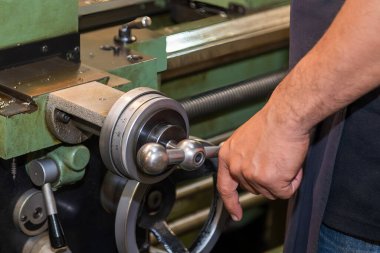 The machine operator working with lathe machine. The metalworking process by turning machine.