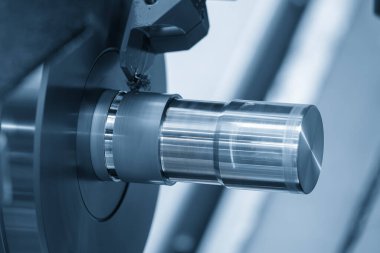CNC torna makinesinin yuvası açık mavi sahnedeki metal şaft parçalarını kesiyor. CNC dönüşüm makinesiyle çalışan yüksek teknoloji metali.