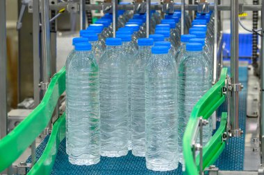  The group of filled drinking water bottles on the conveyor belt. The hi-technology of drinking water manufacturing process. clipart