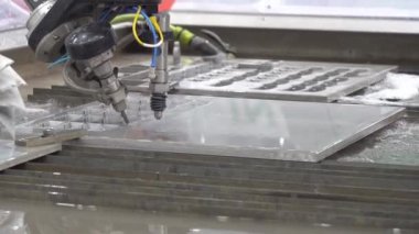 Alüminyum plakayı kesen çok eksenli yıpratıcı su jeti kesme makinesinin yakın çekim sahnesi. CNC makinesiyle çalışan yüksek teknoloji levha metali.
