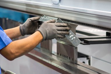 Bükme makinesi operatörünü kapatın ve metal parçaları lastik eldivenle tutun. Yetenek operatörünün kullandığı levha metal çalışması.