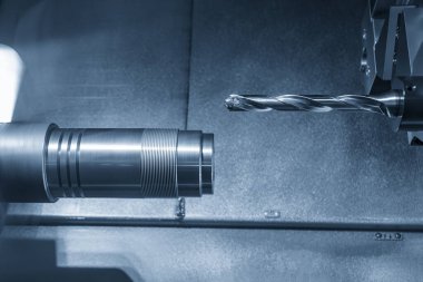 CNC torna makinesi, açık mavi sahnedeki metal parçaları deliyor. Makineyi döndürerek çalışan yüksek teknolojili metal işleme .