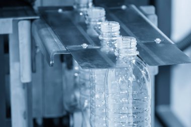 Açık mavi sahnede içme suyu şişesi üfleme makinesiyle üretiliyor. Plastik şişe üfleme makinesi operasyonu..