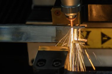 Sahneyi kapatın, fiber lazer kesme makinesi kare şeklindeki paslanmaz çelik tüpü parlak ışıkla kesti. Lazer kesme makinesinin yüksek teknoloji metal üretim süreci.. 