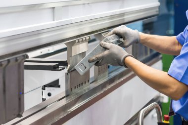 Bükme makinesi operatörünü kapatın ve metal parçaları lastik eldivenle tutun. Yetenek operatörünün kullandığı levha metal çalışması.