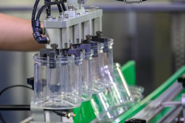 Robot sistem tarafından enjeksiyon makinesinden yapılan yüksek teknoloji madde işleme süreci. Yüksek teknoloji enjeksiyon kalıbıyla geniş şişe üretim süreci.