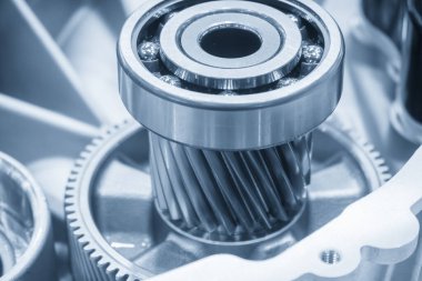 Açık mavi sahnedeki elektrikli araç şanzıman parçalarını kapatın. Elektronik motor için eğim teçhizatı parçalarıyla dönen taşıyıcı.
