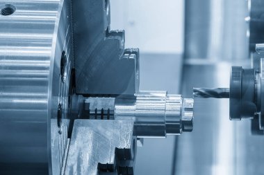 CNC Torna Makinesi, açık mavi sahnedeki metal şaft parçalarını kesti. CNC dönüşüm makinesiyle çalışan yüksek teknoloji metali.