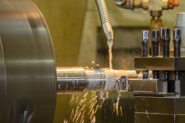 Torna makinesi metal şaft parçalarını sıvı soğutucu metoduyla kesiyor. Makineyi döndürerek metal işleme süreci.