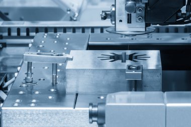 Zar, açık mavi sahnede CNC programı tarafından kablo EDM makine kontrolü ile kesme işlemi uyguluyor. Kalıp yerleştirme parçalarını kesen kablo EDM makinesi yakın çekim sahnesinde. 