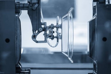 Plastik mutfak, açık mavi sahnede enjeksiyon makinesiyle parça üretim işlemi yapıyor. Robotik sistem tarafından enjeksiyon makinesinden sahne materyali işleme işlemini kapat. 