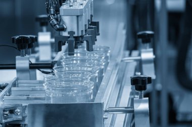 Robot sistem tarafından enjeksiyon makinesinden yapılan yüksek teknoloji madde işleme süreci. Yüksek teknoloji enjeksiyon kalıbıyla geniş şişe üretim süreci.