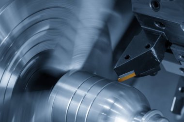 Açık mavi sahnede CNC torna makinesi için kaplama yonga aracı kapatın. CNC dönüşüm makinesinin yüksek teknolojili metal işlemesi .