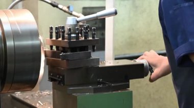 Torna makinesiyle çalışan makine operatörünün metal şaft parçalarıyla kestiği sahne. Makineyi döndürerek metal işleme süreci.