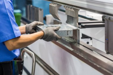 Bükme makinesi operatörünü kapatın ve metal parçaları lastik eldivenle tutun. Yetenek operatörünün kullandığı levha metal çalışması.