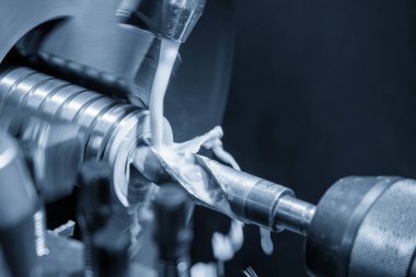 Açık mavi sahnede makine torna delme işlemini sıvı soğutucu metoduyla kapatın. CNC dönüşüm makinesinin yüksek teknolojili metal işlemesi.