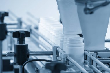 Açık mavi sahnedeki ilaç imalat konseptleri. Dolum işlemi için konveyör bölmesinin üzerindeki ilaç şişesi.. 