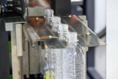 Küf makinesinden sonra konveyör bandındaki içme suyu şişeleri. İçme suyu üretim sürecinin yüksek teknolojisi. 