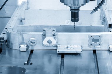 Açık mavi sahnede sondaj aracıyla alüminyum batarya bölmelerinde sondaj makinesi deliği. Elektrikli araç parçaları üretim süreci makine merkezi tarafından.