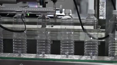 Yavaş çekim sahnesi, taşıyıcı banttaki dolu su şişeleri. İçme suyu üretim sürecinin yüksek teknolojisi. 