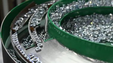 Yavaş çekim sahnesi kare şekilli, vibrasyon besleme makinesiyle otomatik fındık besleyicisi. Çelik fındık işleme süreci.