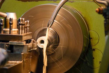 Torna makinesi metal şaft parçalarını sıvı soğutucu metoduyla kesiyor. Makineyi döndürerek metal işleme süreci.