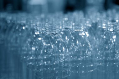 Açık mavi sahnede su şişeleri grubu. İçme suyu üretim sürecinin yüksek teknolojisi. 