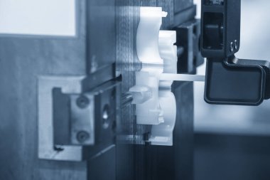 Açık mavi sahnedeki enjeksiyon makinesinin plastik parçalarını kapatın. Plastik enjeksiyon küf makinesinin otomotiv parçaları üretim süreci.