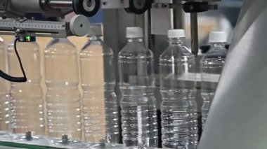 Yavaş çekim sahnesi, taşıyıcı banttaki dolu su şişeleri. İçme suyu üretim sürecinin yüksek teknolojisi. 