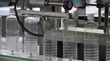 Yavaş çekim sahnesi. Taşıyıcı banttaki içme suyu şişeleri. İçme suyu üretim sürecinin yüksek teknolojisi. 