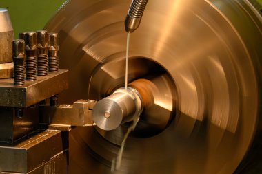 Torna makinesi metal şaft parçalarını sıvı soğutucu metoduyla kesiyor. Makineyi döndürerek metal işleme süreci.