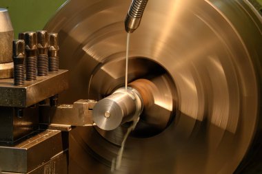 Torna makinesi metal şaft parçalarını sıvı soğutucu metoduyla kesiyor. Makineyi döndürerek metal işleme süreci.