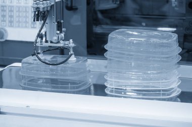 Mavi tondaki enjeksiyon makinesinde otomatik madde işleme işlemi. Plastik enjeksiyon küf makinesinden otomatik sistem tarafından üretilen gıda konteynırı.