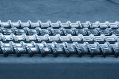 Açık mavi sahnede, enjeksiyon makinesinin namlu vidasının yedek parçalarını kapatın. Üretim konsept enjeksiyon makinesi .