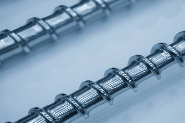 Açık mavi sahnede, enjeksiyon makinesinin namlu vidasının yedek parçalarını kapatın. Üretim konsept enjeksiyon makinesi .