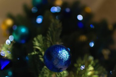 Arka planda Bokeh ışıkları olan mavi top Noel ağacında. Noel süslemeleri