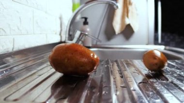 Islak patatesler mutfak lavabosunda yuvarlanıyor.