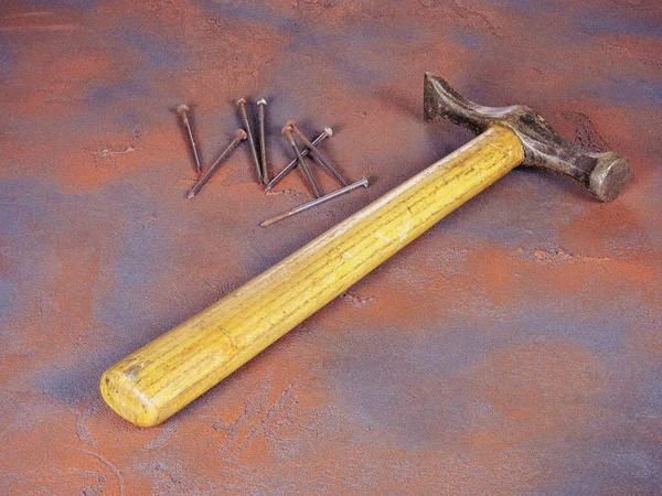 木製のハンドルとグランジスタイルの背景に錆びた釘の束を持つ古いハンマー — ストック写真