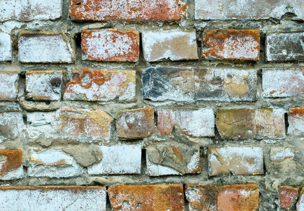 The old crumbling brick wall is weathered and collapsed