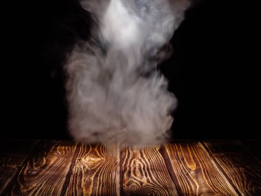 Tahta bir tahtanın üstünde siyah bir zeminde beyaz duman bulutu.