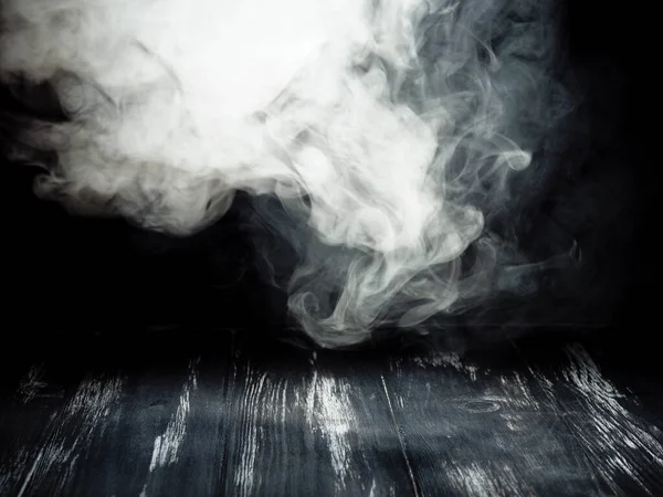 Ahşap bir tahtanın üzerinde siyah arka planda beyaz duman kütleleri