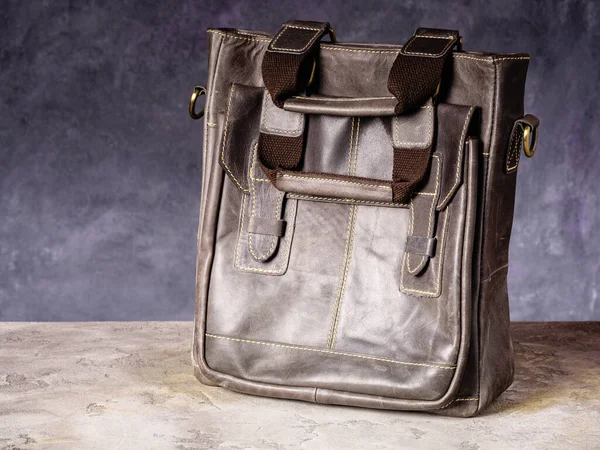 Brown leather business everyday bag with handles on a gray concrete background