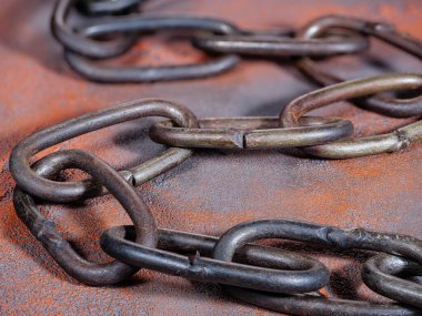 Turuncu bir arka planda eski paslı zincir.