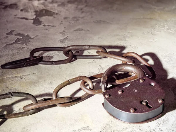 stock image Old rusty link chain and padlock on concrete background, metal texture close-up